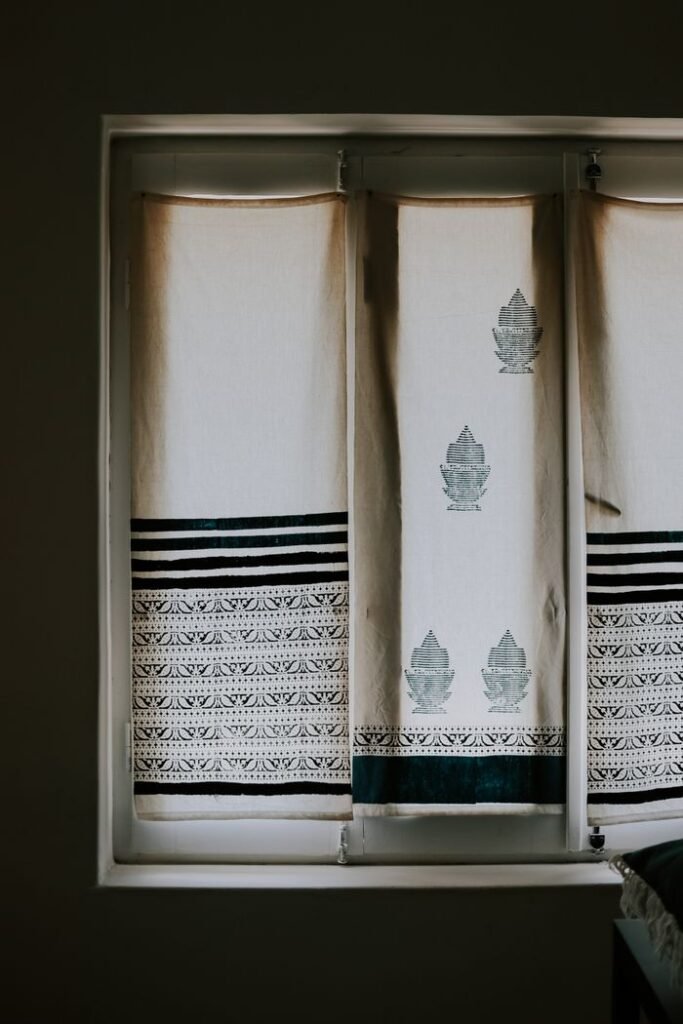 Minimalistic window curtains with intricate ethnic designs filtering soft daylight indoors.
