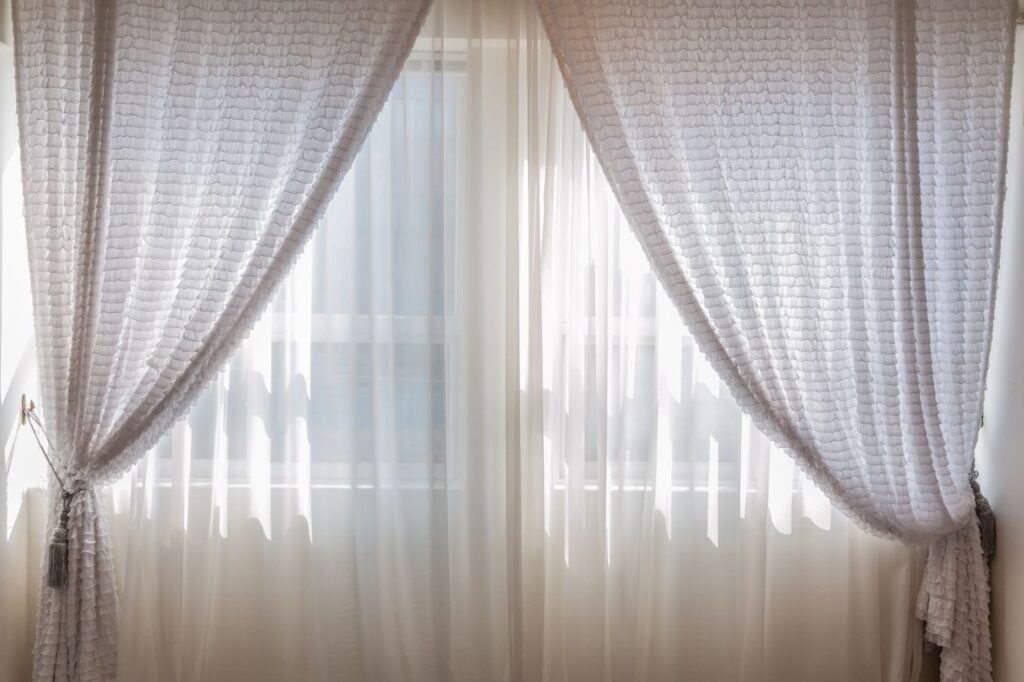 Sun shining through elegant white curtains in a cozy, modern interior setting.
